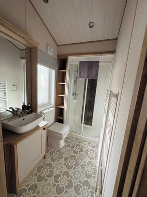 A compact bathroom with a sink, toilet, and shower. - Luxury Harrogate Lodge South Facing Decking (Holsworthy)