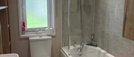 A bathroom with a toilet, sink, bathtub, and shower.