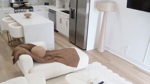 Une cuisine moderne avec des meubles blancs, des appareils en acier inoxydable et un îlot central.