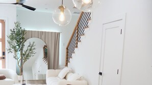 Un salon moderne avec un canapé blanc, une table à manger et un escalier.