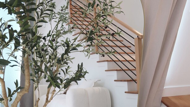 Un intérieur moderne avec un escalier, un canapé blanc et un arbre en pot.