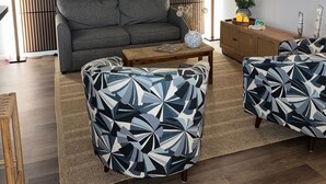 Un soggiorno moderno con un divano, due poltrone fantasia, un tavolino da caffè e una televisione a parete.