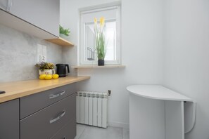 Eine moderne Küche mit Holzarbeitsplatte, Einbauherd, weißem Heizkörper und einem Fenster mit Pflanze.