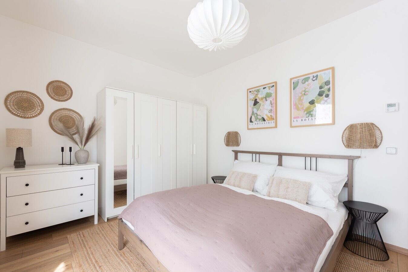 Een slaapkamer met een bed, een kaptafel, een kledingkast en twee kunstwerken aan de muur.