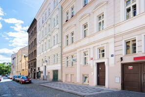 Eine Reihe historischer Gebäude mit einer gepflasterten Straße, parkenden Autos und einem sichtbaren Geschäft mit einer Schaufensterschild.