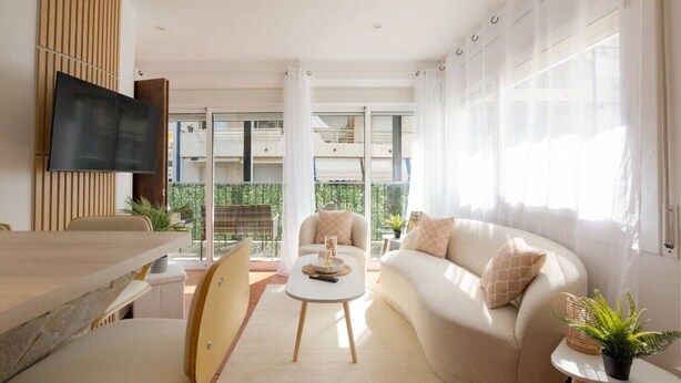 Uma sala de estar moderna com sofá, cadeiras, mesa de centro, televisão e varanda com vista.
