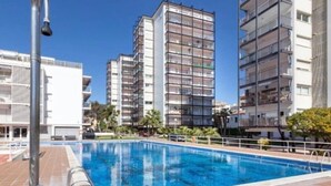 Piscina com deck revestido, cercada por edifícios residenciais altos.