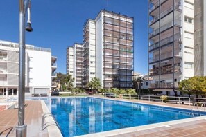 Ein Schwimmbecken mit gefliestem Sonnendeck, umgeben von mehrstöckigen Wohngebäuden.