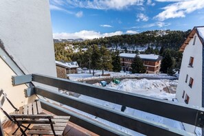 Un balcon offrant une vue sur un paysage enneigé, des bâtiments et un ciel dégagé.