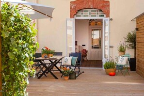 Eine Terrasse im Freien mit Holzdeck, Tisch, Stühlen und Pflanzkübeln.