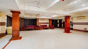 A spacious hotel lobby with multiple seating areas, ceiling fans, and a fire extinguisher. - Deluxe Banshi Bhawan (Prayagraj)
