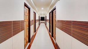 A long, narrow hallway with doors on both sides, leading to a dark room at the end. - Deluxe Banshi Bhawan (Prayagraj)