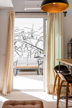 Ein modernes Zimmer mit einer Schiebeglasdoor, einem Essbereich mit Holztisch und -stühlen sowie einer großen Pendelleuchte.