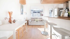Et moderne køkken med spiseplads, en sofa og et stort vindue med udsigt over byen.
