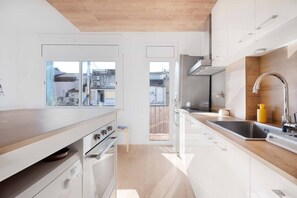 A modern kitchen with a wooden countertop, stainless steel sink, and a view through a glass door. - Cute Apartment in the Heart of Vilanova | Virgi By Palmera (Vilanova i la Geltrú)