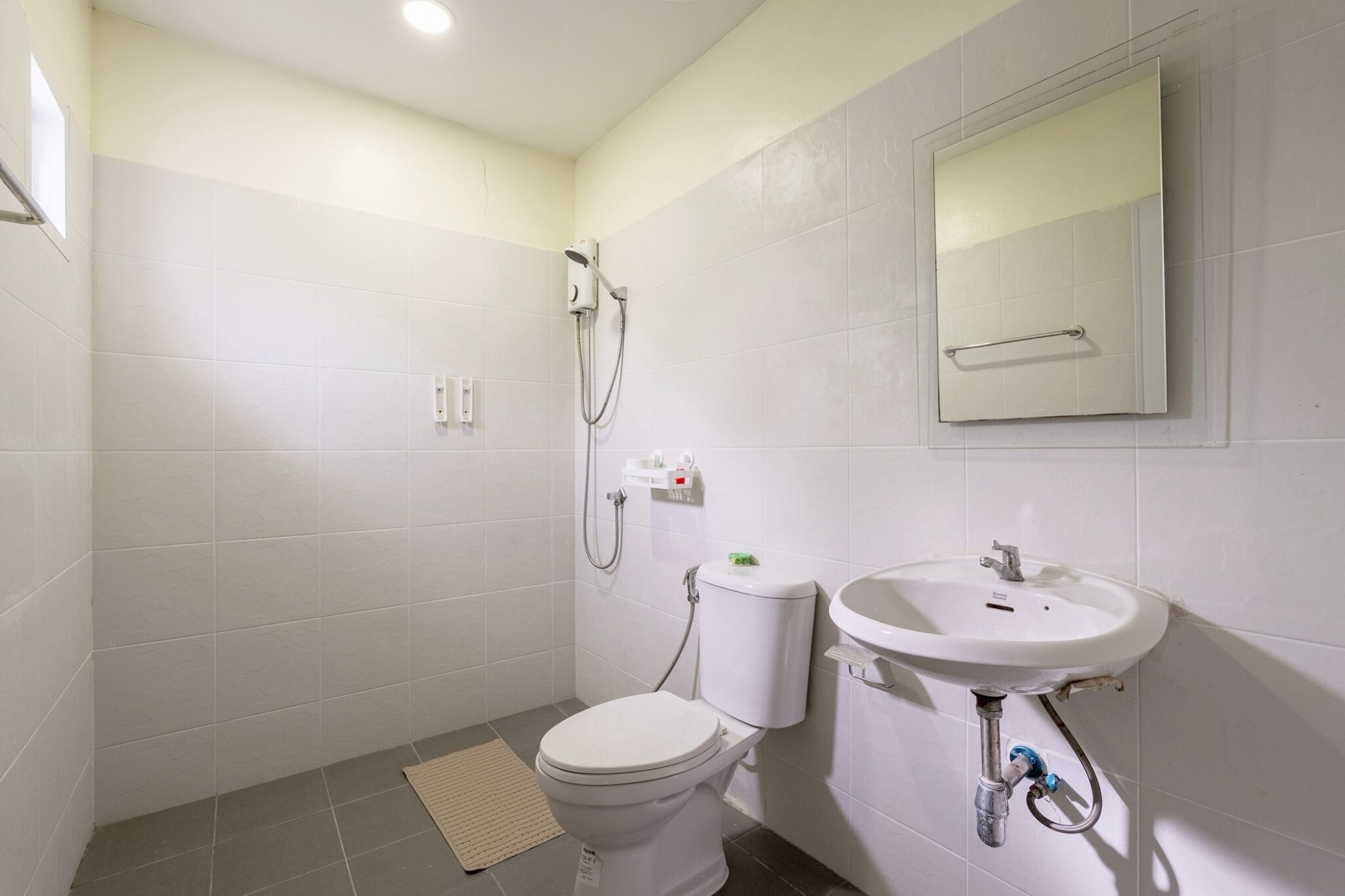 Un baño con inodoro, lavamanos, ducha y espejo.