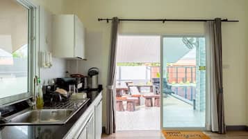 A kitchen with a sink, cabinets, and a dining area with outdoor seating.