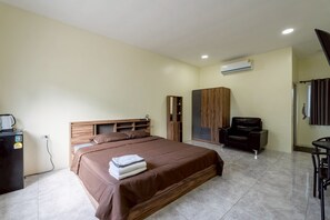 Un dormitorio con cama, armario, zona de estar y una pequeña mesa.