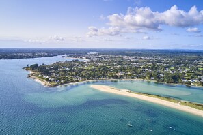 Luftaufnahme einer Küstenstadt mit Strand, klarem Wasser und einer Mischung aus Wohn- und Geschäftsgebäuden.