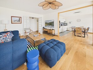 Ein modernes Wohnzimmer mit einer Couch, einem Hocker und einem Essbereich.