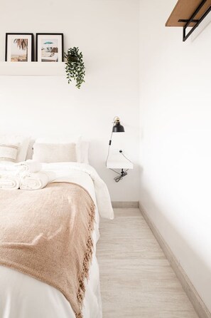 A neatly arranged bedroom with a bed, pillows, a bedside lamp, and wall-mounted artwork. - Sunny & Stylish Apartment with A/C | Trini by Palmera (Sant Pere de Ribes)