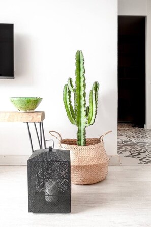 A cactus in a woven pot, a black textured sculpture, and a wooden table with a bowl. - Sunny & Stylish Apartment with A/C | Trini by Palmera (Sant Pere de Ribes)