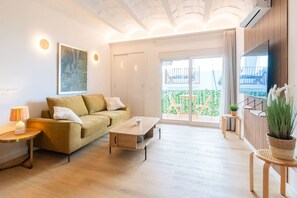 Una sala de estar moderna con un sofá, una mesa de centro y un televisor montado en la pared.