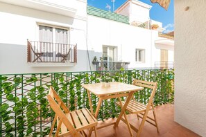 A balcony with a table and chairs, a green plant wall, and a white building with windows and a balcony. - 100 m from the Beach - Downtown Sitges | Sebas by PG (Sitges)