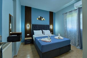 Una habitación de hotel con cama, mesitas de noche, un espejo y una lámpara fijada a la pared.