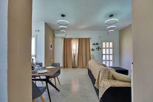Una habitación con una mesa de comedor, sillas, un sofá, una cama y una ventana con cortinas.