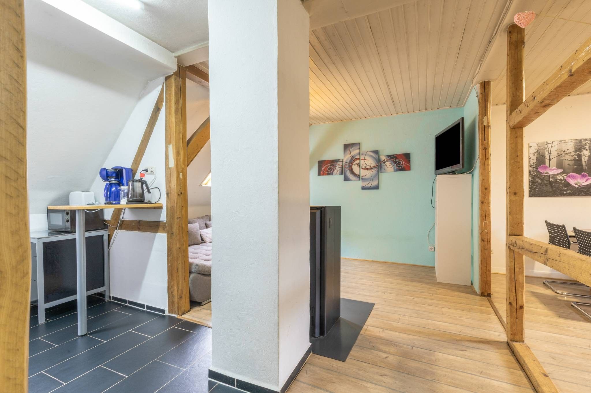 A modern interior with a kitchen area, a seating area with a sofa, and a dining table.