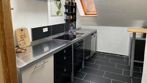 A modern kitchen with a black countertop, stainless steel appliances, and a black and white tile floor.