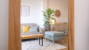 Ein modernes Wohnzimmer mit einer Couch, einem Couchtisch, einem Beistelltisch, einer Topfpflanze und einem dekorativen Spiegel.