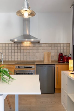 Una cocina moderna con campana de acero inoxidable, lavavajillas, estufa y cafetera.