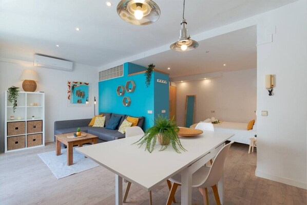 Ein modernes Wohnzimmer mit einer Couch, einem Esstisch und einer Küchenzeile.