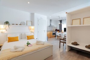 Ein modernes Hotelzimmer mit Bett, Nachttisch und Blick in den Küchenbereich.