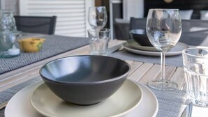 Une table à manger dressée avec un saladier, des assiettes, des verres et des couverts.