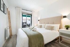 A hotel room with a bed, a bedside table with a plant, a window with curtains, and a radiator. - Modern Apartment w/ big Patio | Maria by Palmera (Sant Pere de Ribes)