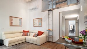 A living room with a sofa, a coffee table with fruits and drinks, and a ladder against the wall. - Donna Angelina Arena View (Verona)