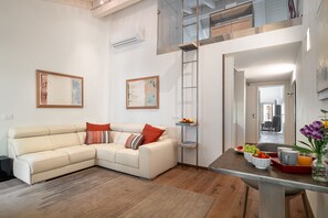 A living room with a sofa, a coffee table with fruits and drinks, and a ladder against the wall. - Donna Angelina Arena View (Verona)