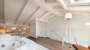 A modern bathroom with a large bathtub, wooden flooring, a glass shower enclosure, and a staircase leading to an upper level. - Donna Angelina Arena View (Verona)
