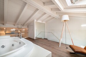 A modern bathroom with a large bathtub, wooden flooring, a glass shower enclosure, and a staircase leading to an upper level. - Donna Angelina Arena View (Verona)