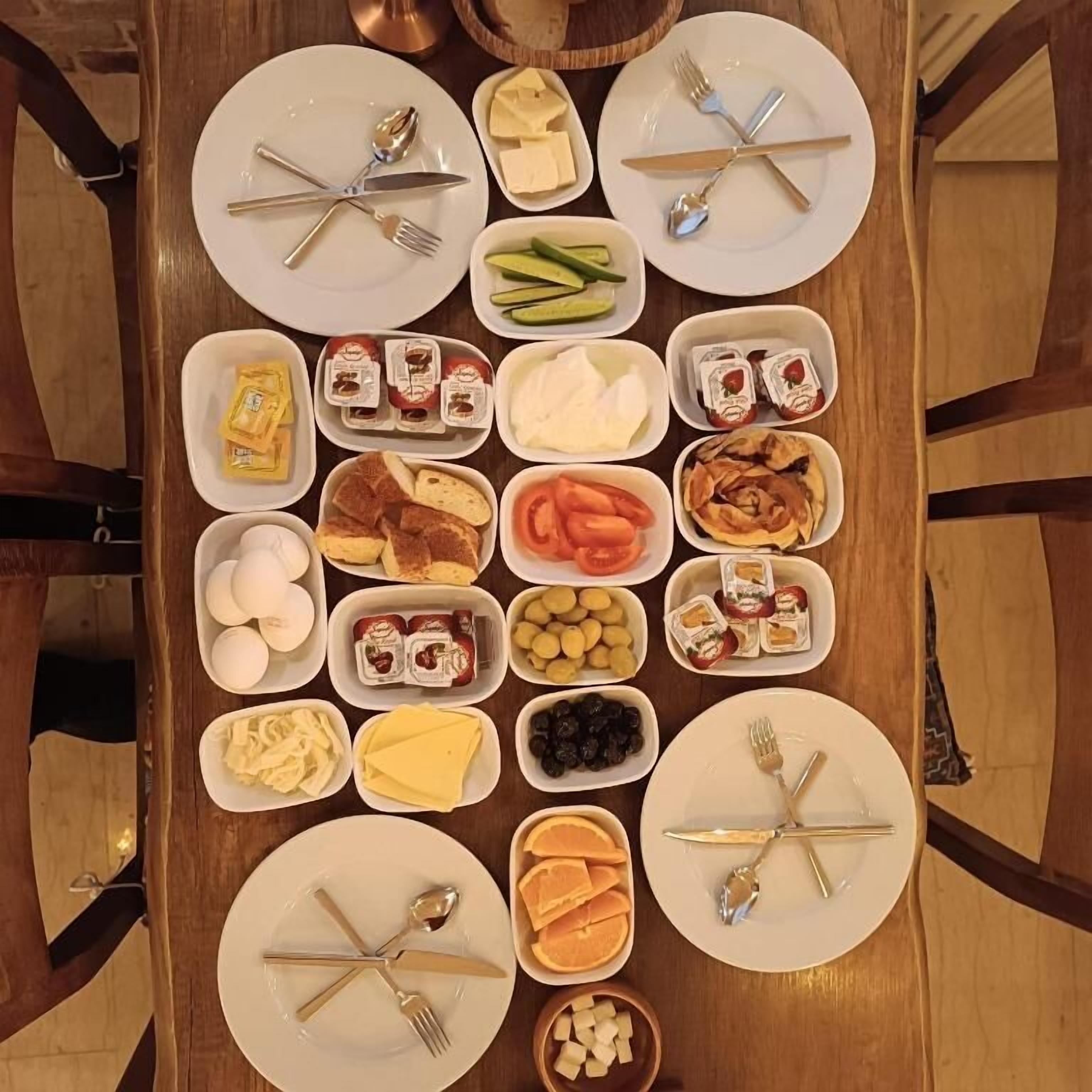 Un buffet de petit-déjeuner avec divers aliments et ustensiles disposés sur une table en bois.