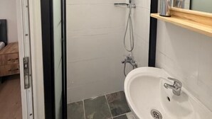 A bathroom with a glass shower enclosure, a sink, and a mirror. - walkabout apart (fatih)