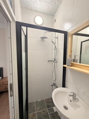Ein Badezimmer mit Duschkabine aus Glas, Waschbecken und Spiegel.