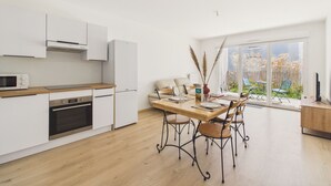 Et moderne køkken med hvide skabe, en træbordplade og et spiseområde med et bord og stole.