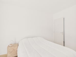 Ein schlicht eingerichtetes Schlafzimmer mit Bett, Nachttisch und Tür.