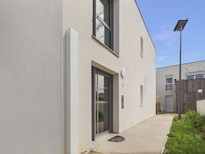 Ein modernes Gebäude mit flacher Fassade, einer großen Glastür und einem kleinen Fenster.