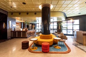 Eine Lobby mit einer zentralen Sitzecke, einem Empfangsbereich und einer Bar.