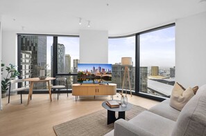 Ein modernes Wohnzimmer mit Blick auf die Stadt, ein Essbereich mit rundem Tisch und ein großes Fenster.